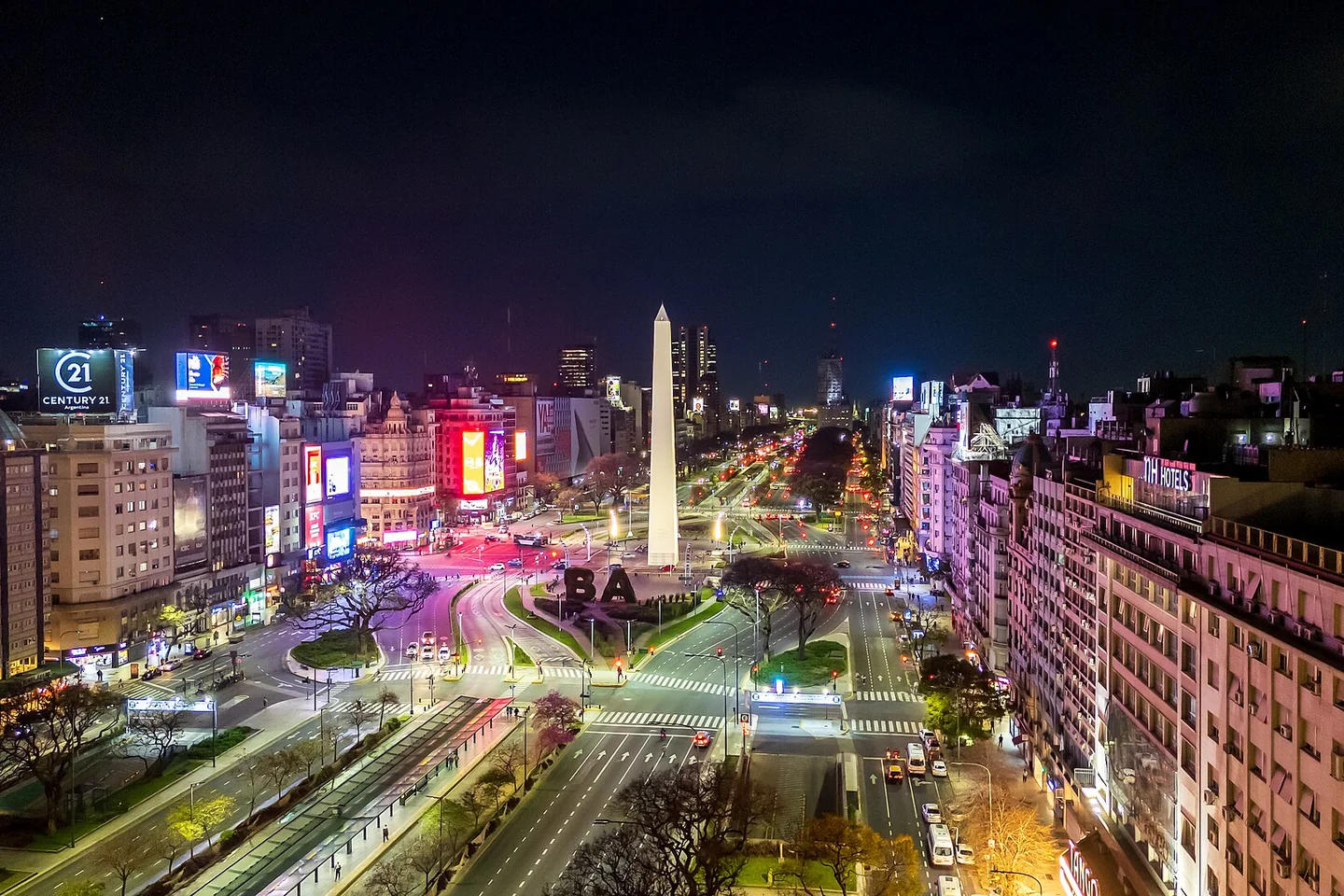 El Obelisco iluminado se alza sobre la avenida 9 de Julio y las luces de Buenos Aires por la noche.
