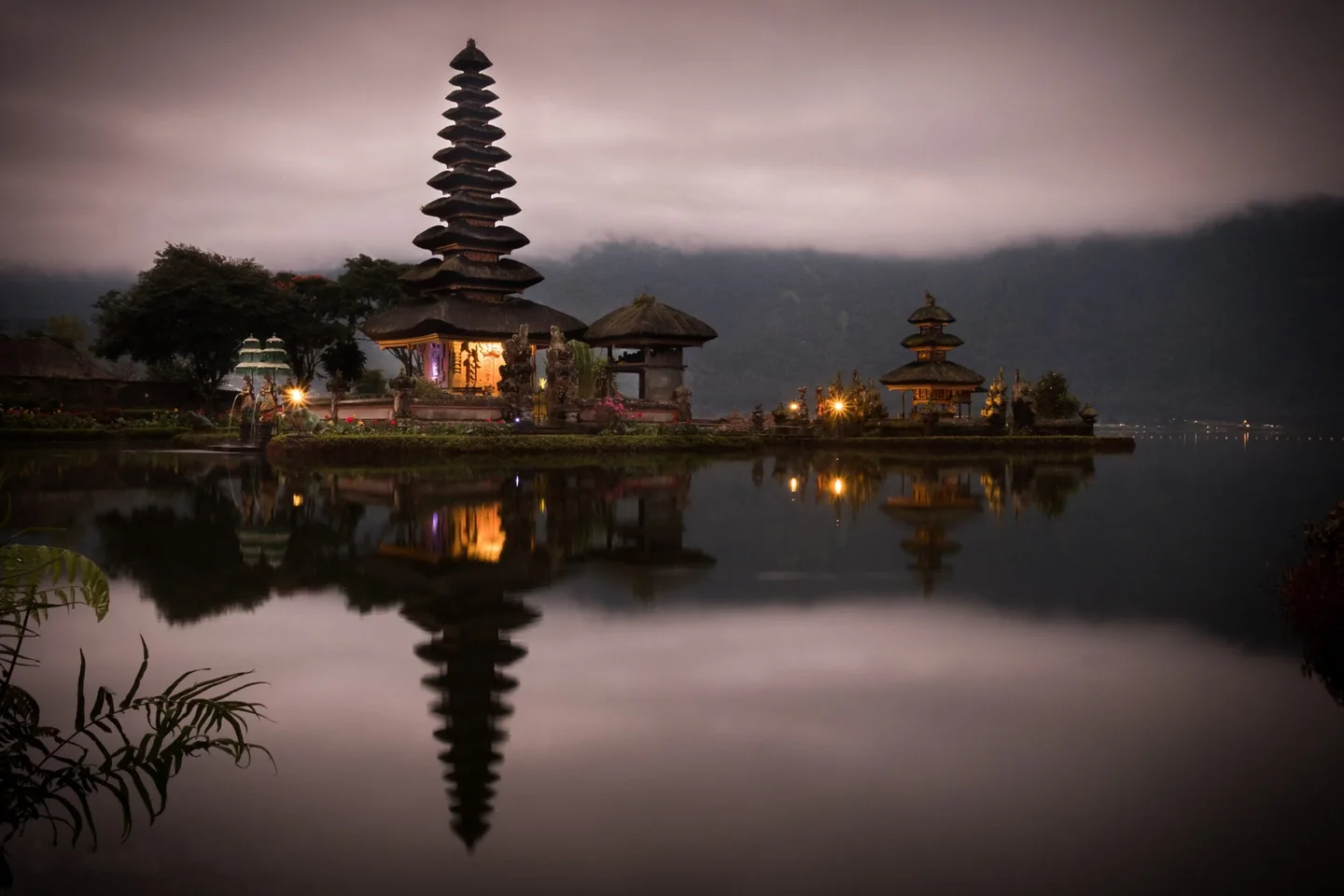 The tiered roofs of Ulun Danu Bratan temple reflected in the calm waters of Lake Bratan at dawn.