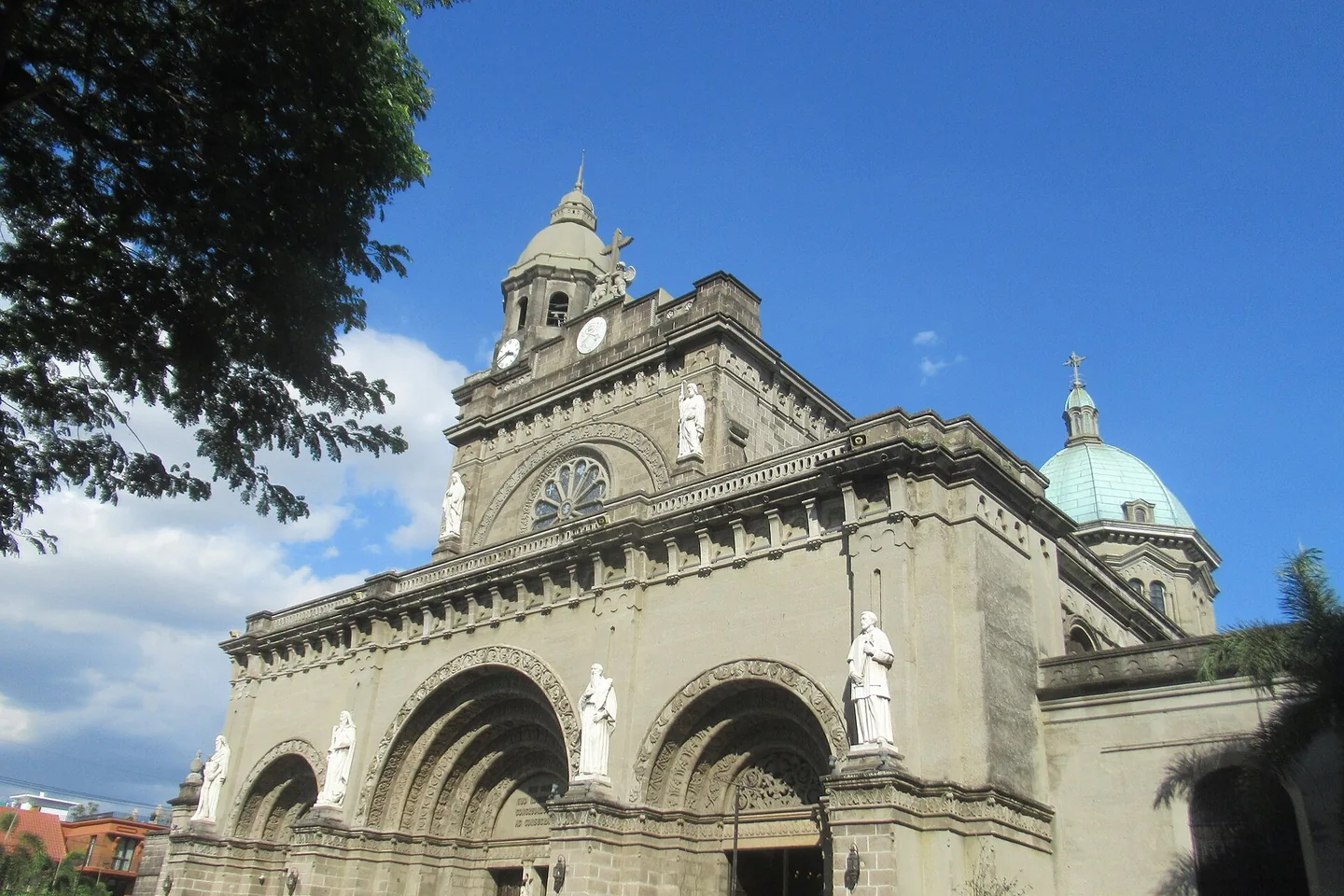 The stone façade and dome of Manila Cathedral in Intramuros beneath a vivid blue sky.