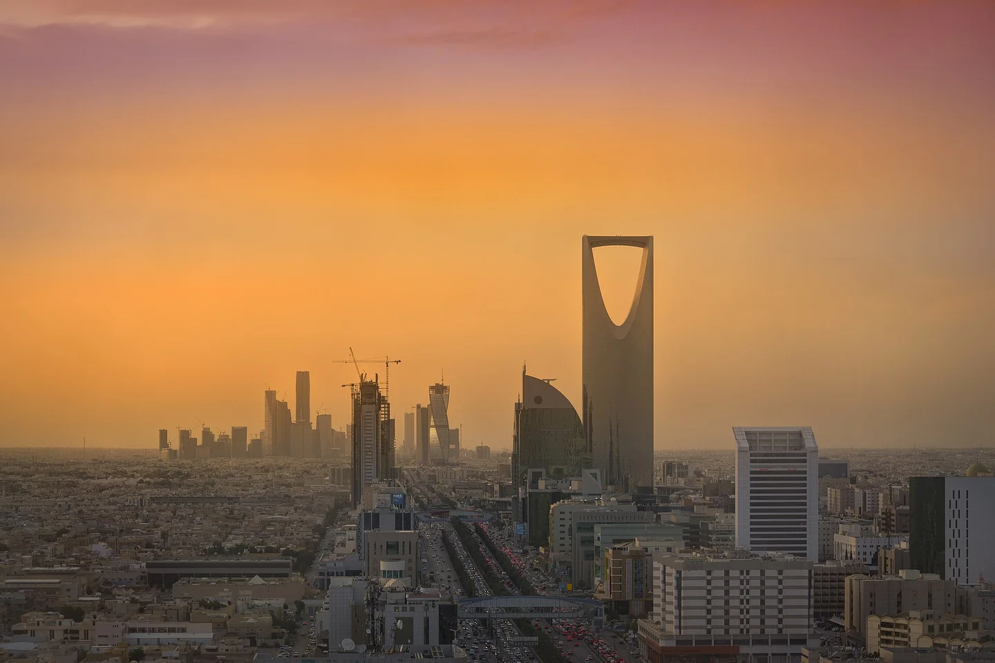 يرتفع مركز المملكة بفتحته المميزة في أعلى البرج فوق أفق الرياض في ضوء غروب الشمس الدافئ.